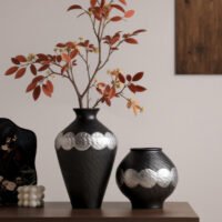 Handmade wabi-sabi style silver-glazed ceramic vase on a minimalist wooden table